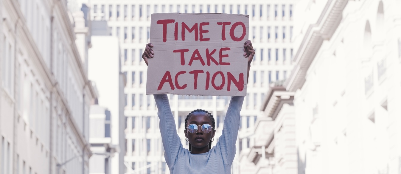 A person holding a sign that reads Time to Take Action